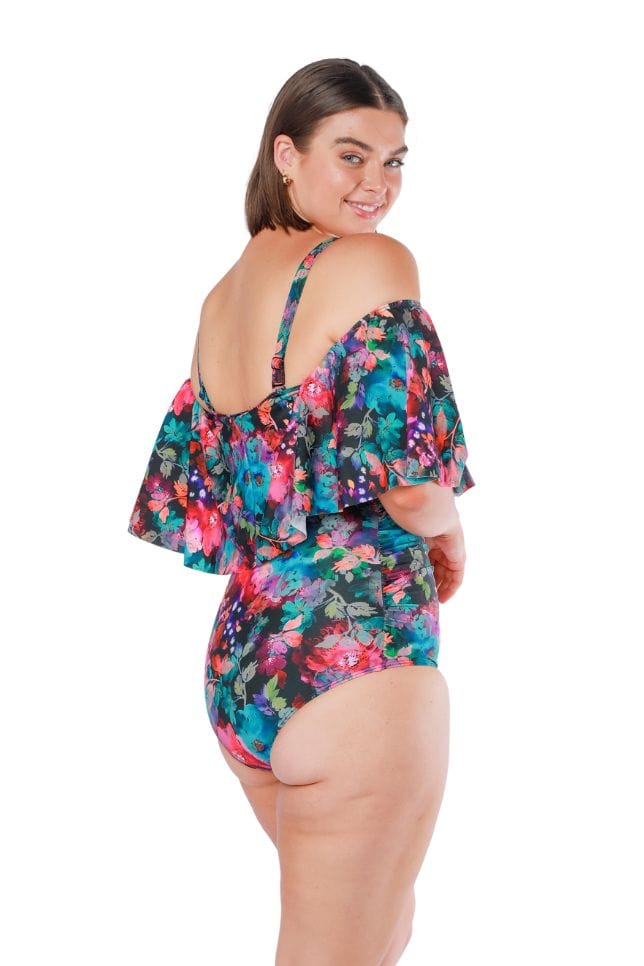Side shot of model wearing off shoulder frill top one piece in pink and blue floral print