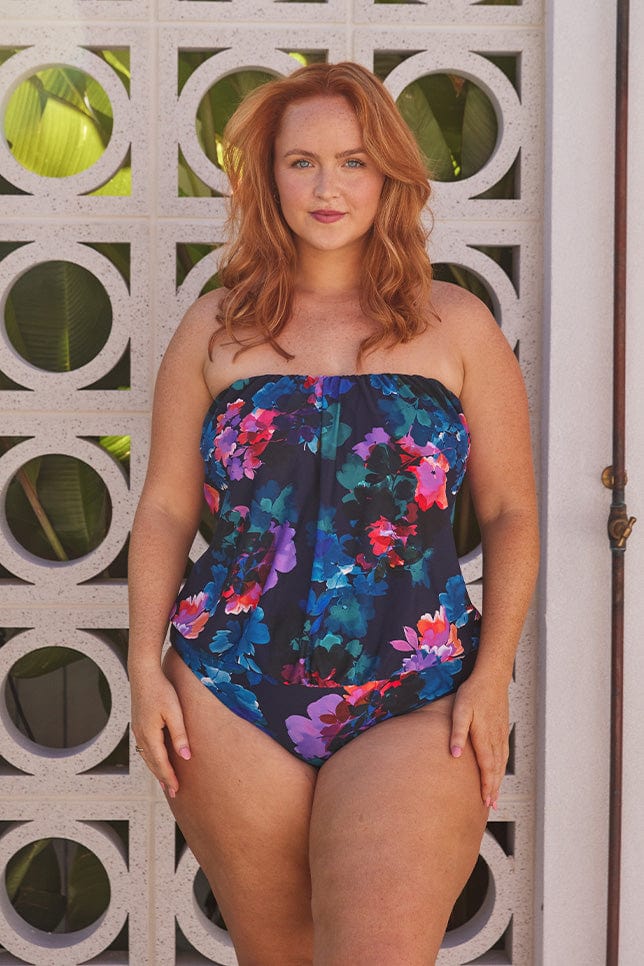 Red hair model wears navy floral flouncy bandeau one piece swimsuit