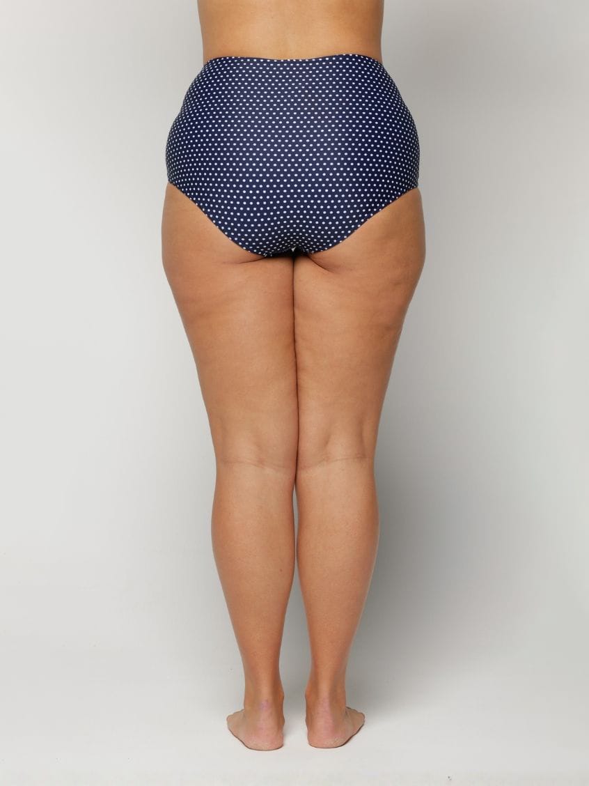 Navy blue polka dot high-waisted bikini bottom on a plain background