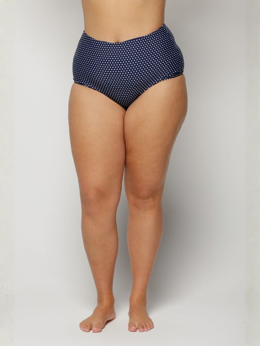 Woman wearing navy high-waisted bikini bottoms with a subtle pattern on a plain background