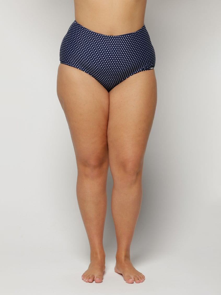 Navy blue polka dot high-waisted bikini bottom on a plain background
