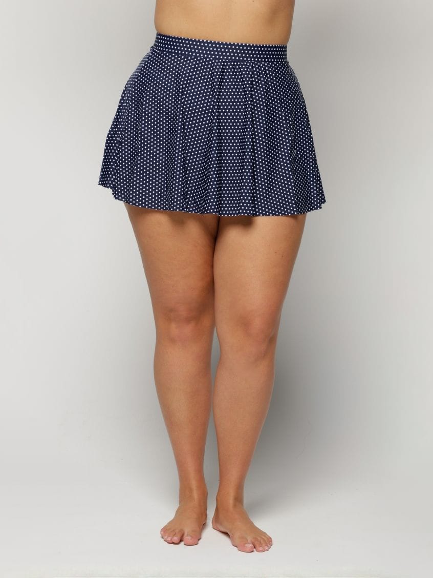 Navy polka dot skirt worn by a woman on a white background