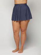 Navy polka dot skirt worn by a woman on a plain background
