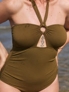 Model wears textured olive green one piece with removable halter neck