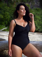 Model wearing black slimming criss cross one piece bathing suit