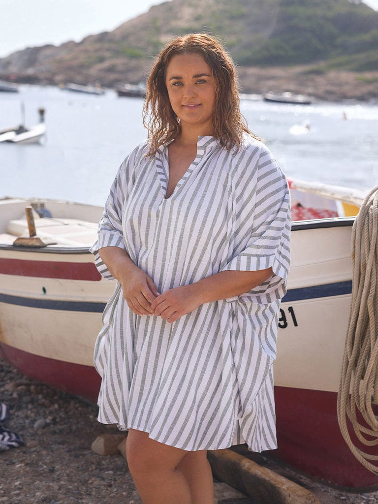Brunette woman by the sea wearing a v neck oversized shirt in green and white
