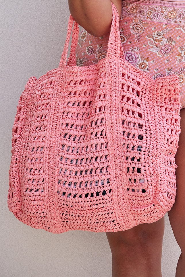 Light pink woven beach bag being held on arm