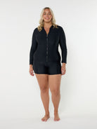 Woman wearing a rash black zip-up swimsuit top on a white background