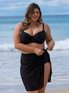 Woman wearing a black bikini and sarong on a beach