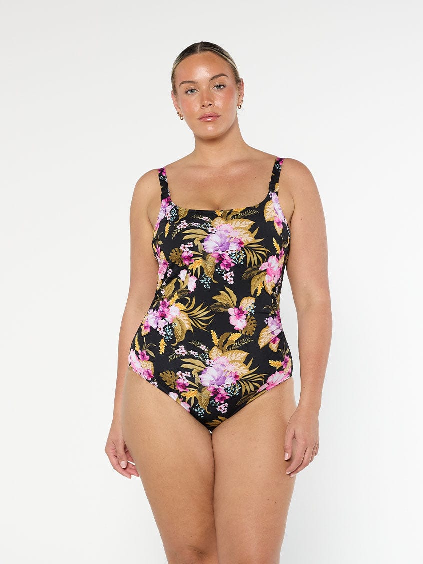 Blonde model wears flattering chlorine resistant one piece swimsuit in gold and pink florals