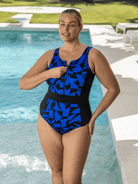 Woman wearing a blue and black patterned chlorine resistant swimsuit by a pool