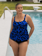Woman wearing a blue and black patterned chlorine resistant tankini by a pool