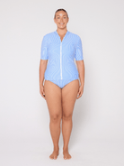 Woman wearing a light blue swimsuit with a zipper on a white background