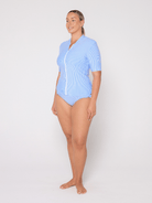 Woman wearing a light blue rash vets with a white background