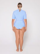 Person wearing a light blue short sleeve rash vest on a white background