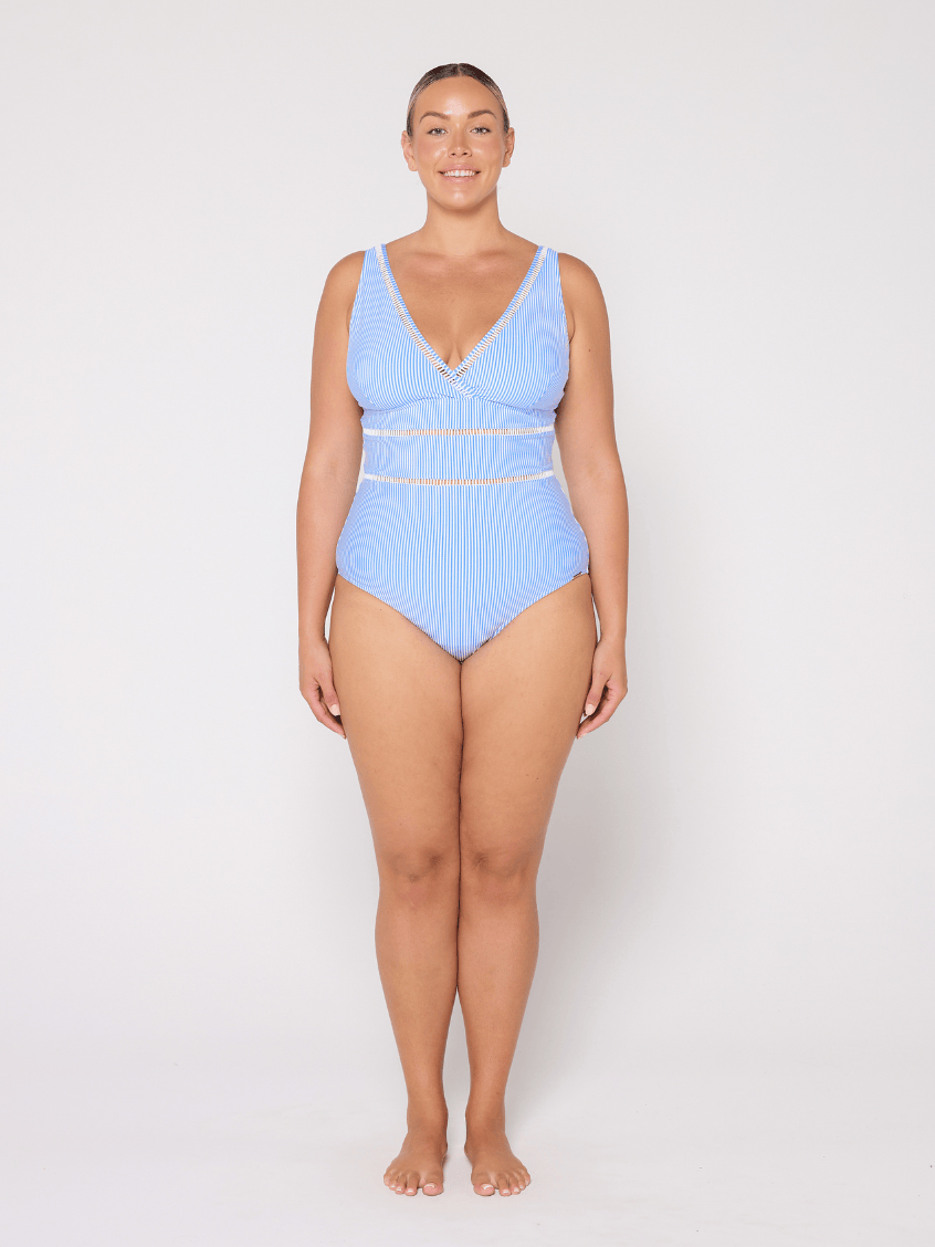 Woman wearing a blue V neck one piece swimsuit on a white background