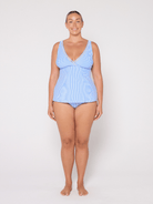 Woman wearing a light blue striped tankini against a white background