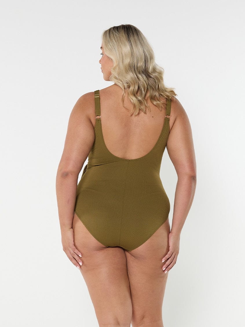 Blonde model wears textured olive green one piece with low scoop back and adjustable straps