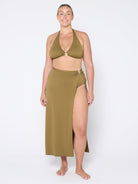 Woman wearing a green bikini set with a long skirt on a white background