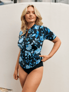 Side profile of model wearing a short sleeve rash vest with full zip through in blue floral