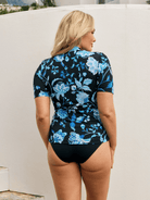 Back of model wearing a short sleeve rash vest in corsica turquoise floral print