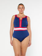 model wearing navy, red and white sporty swimsuit with zip front