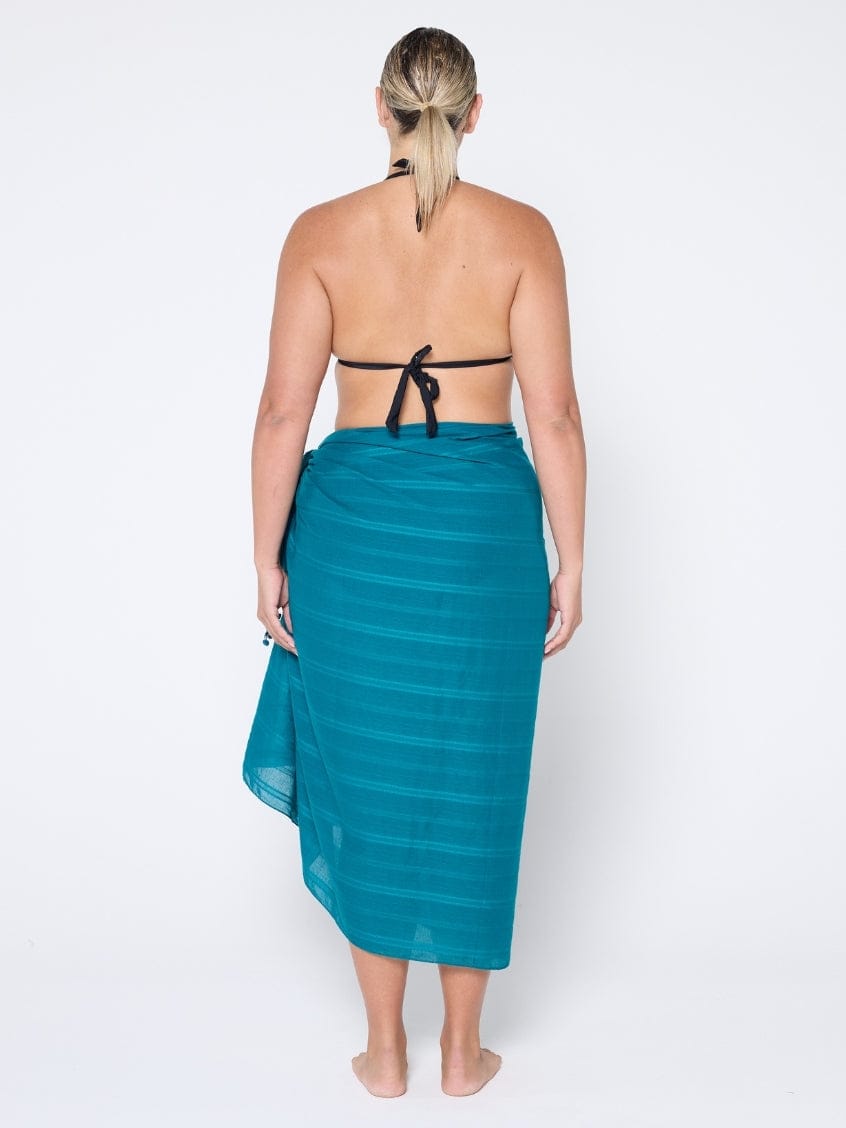 Woman wearing a teal sarong on a white background