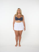 Woman wearing a navy patterned top and white shorts on a white background