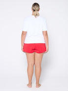Person wearing a white t-shirt and red shorts on a plain background