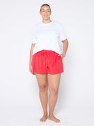 Person wearing red shorts and a white top on a white background
