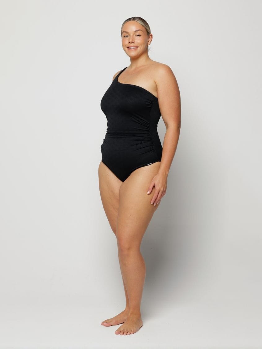 Woman wearing a black one-shoulder swimsuit on a white background