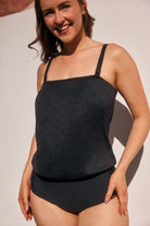 Woman wearing a black tank top and high-waisted shorts against a neutral background