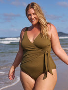 Blonde model wears textured khaki one piece with v neckline and tie side detail