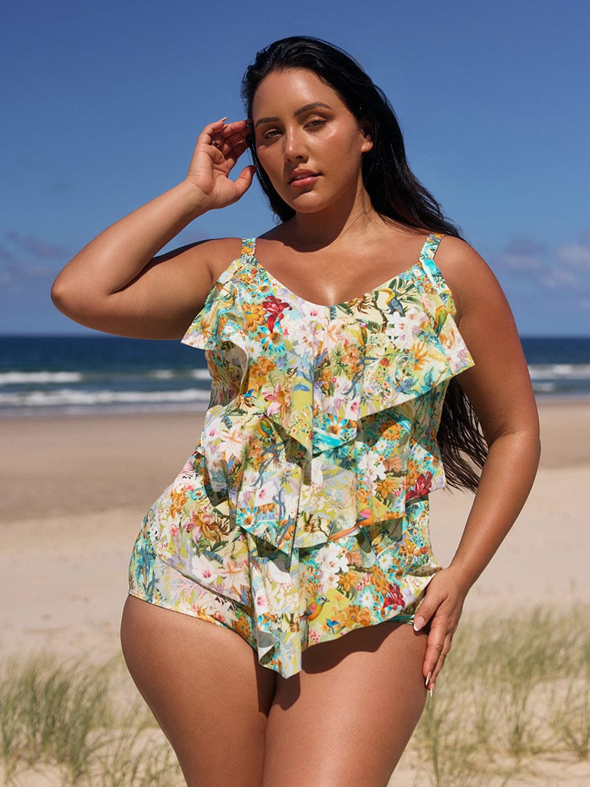 Woman in a floral swimsuit standing on a beach with ocean view