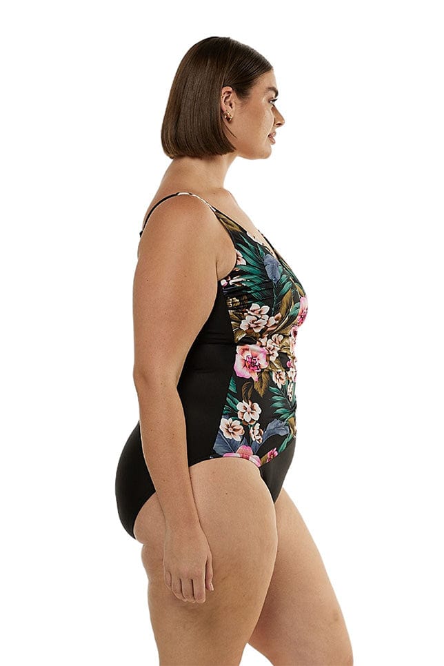 Brunette model showing side of black floral swimsuit
