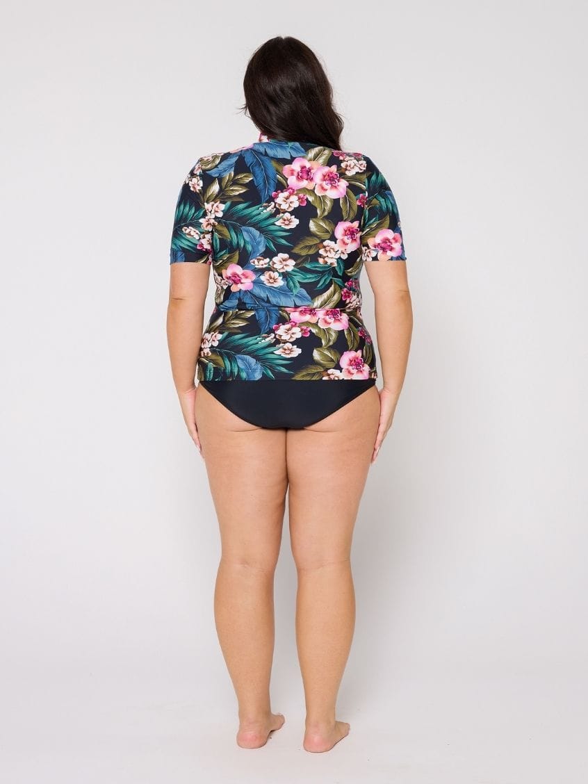 Model in studio wearing a floral short sleeve rash vest with zip front detail