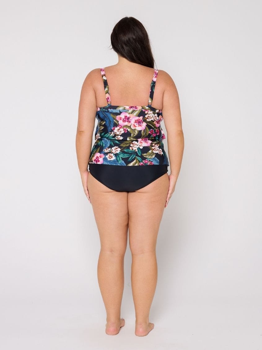 Woman in studio wearing a ruffle tankini top with adjustable straps in floral print