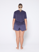 Person wearing a navy t-shirt and shorts set on a white background