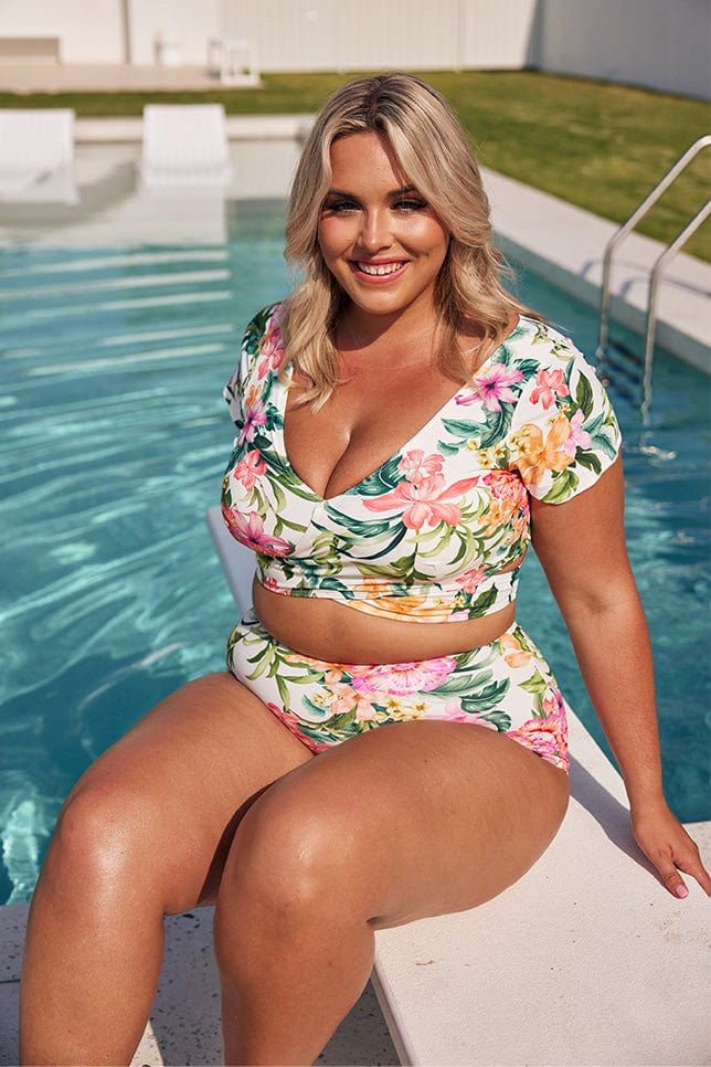 Blonde model wearing white floral wrap bikini top and high waisted pant