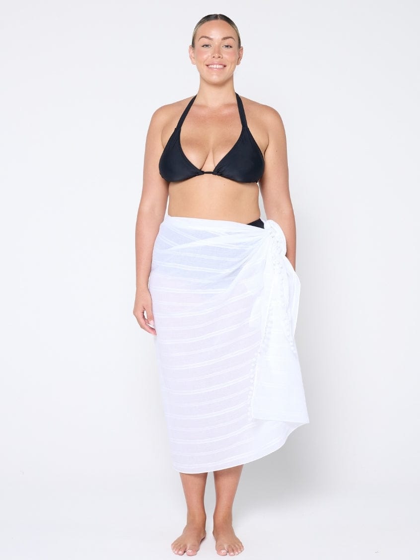 model standing in front of a white wall wearing a white cotton sarong

