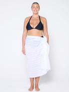 model standing in front of a white wall wearing a white cotton sarong
