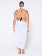 Woman wearing a white sarong over a black bikini on a white background