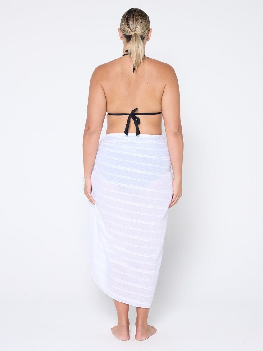 Woman wearing a white sarong over a black bikini on a white background