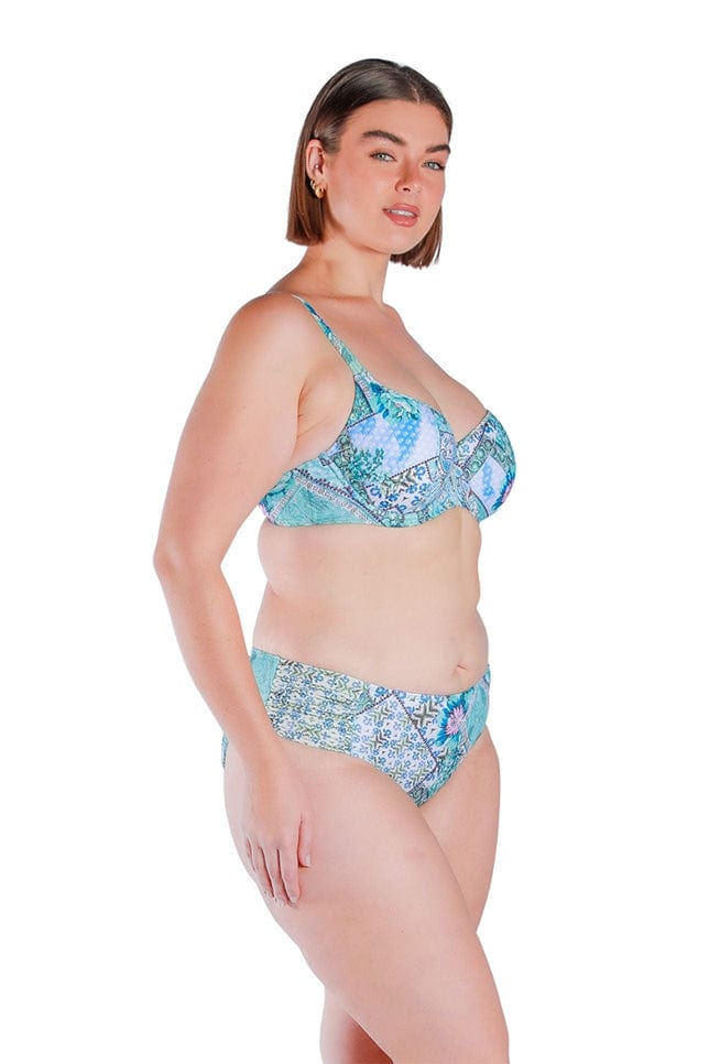 side profile of model wearing a blue and white patchwork printed swim pant with side ruching