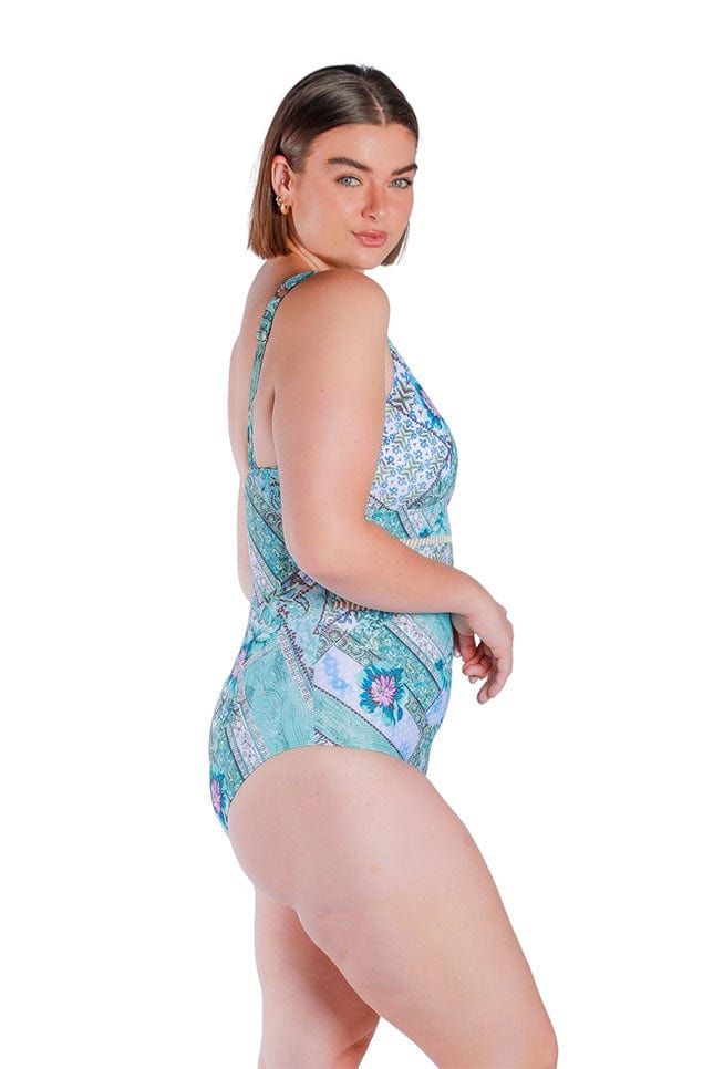 side profile of model wearing a v neckline swimsuit in blue and white tile print