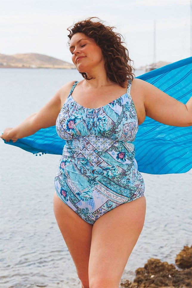 brunette model wearing a underwire one piece swimsuit in aqua blue patchwork print