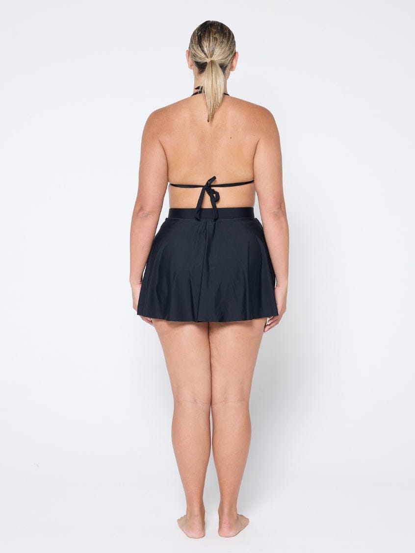 Person wearing a black halter top and skirt set on a white background