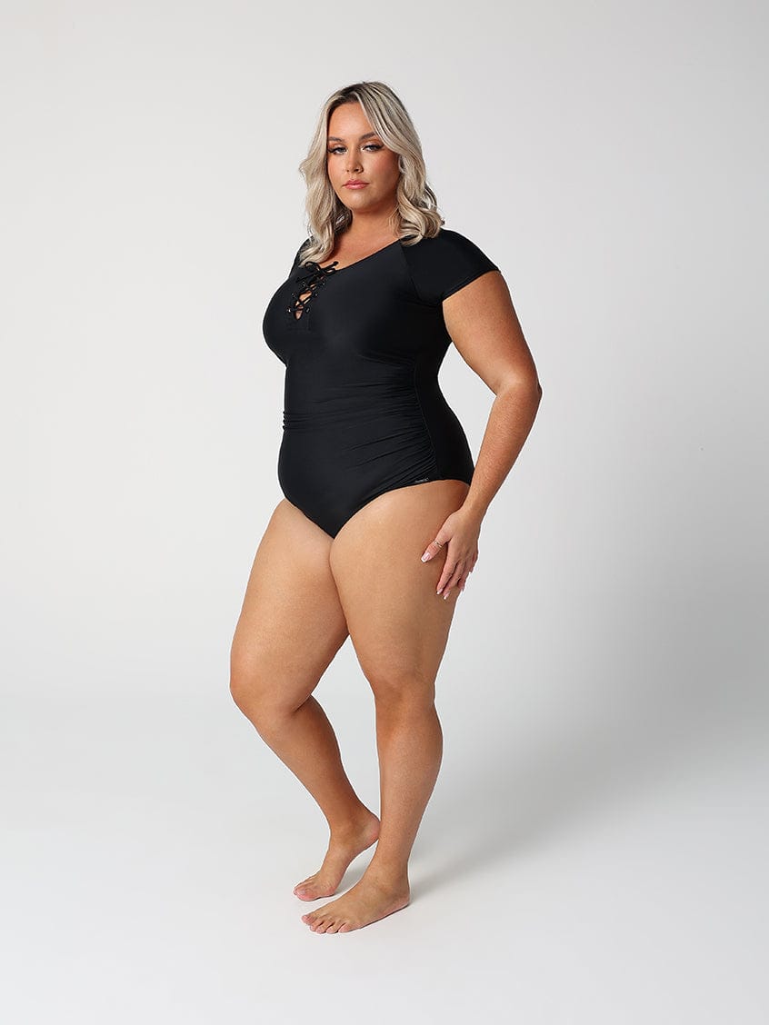 Woman wearing a black bodysuit against a white background
