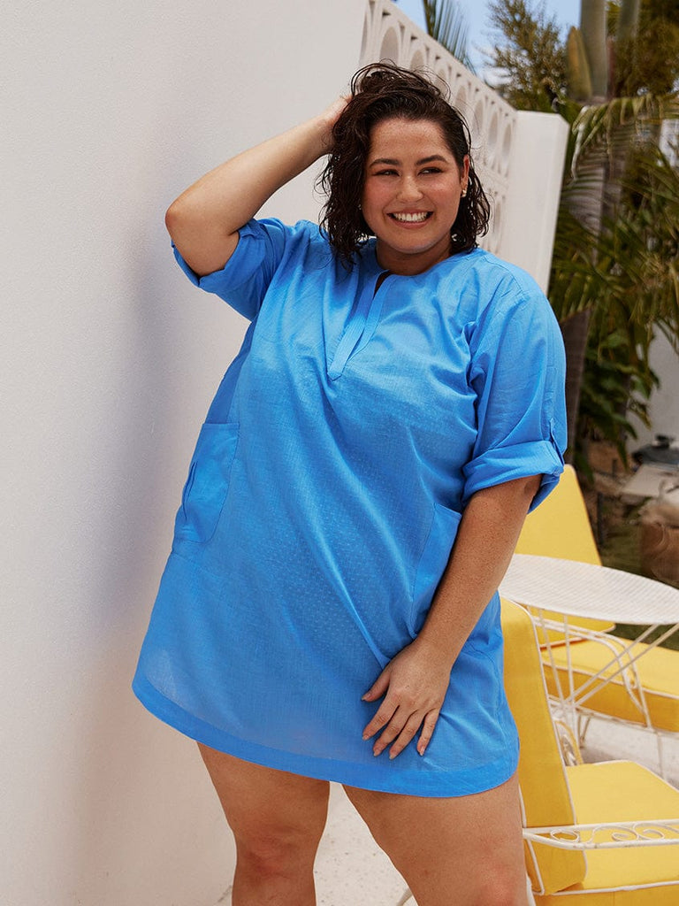 brunette model wears light blue over shirt with roll up sleeves
