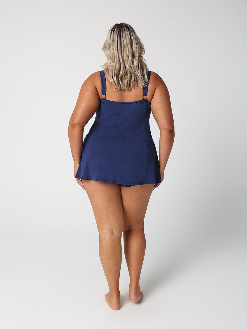 Person wearing a navy blue slip dress on a white background